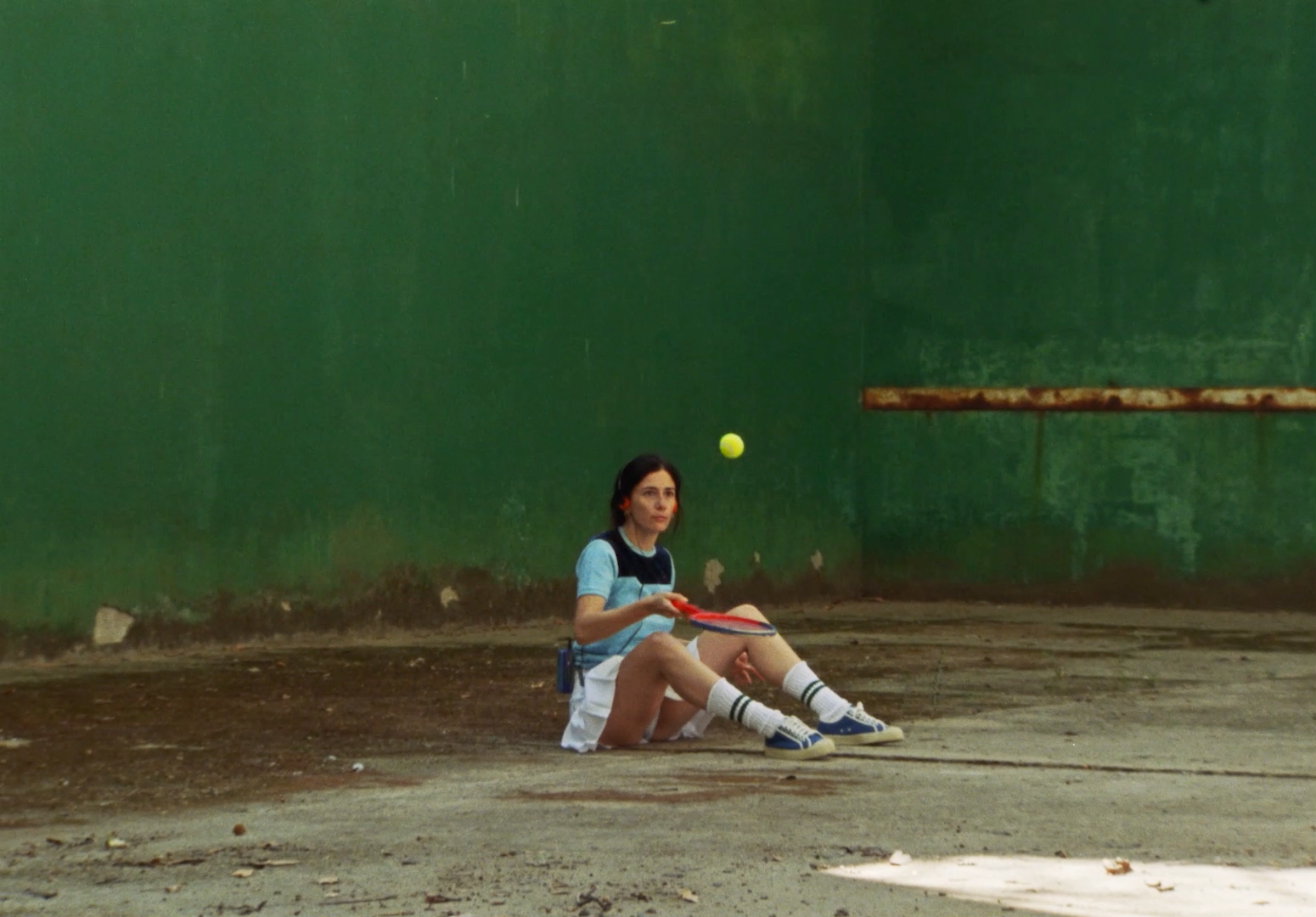 a woman sitting on the ground with a tennis racket