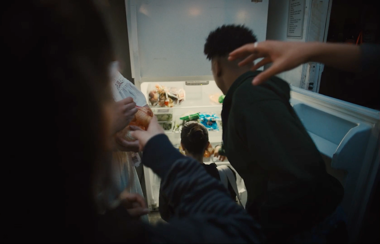 a group of people standing in front of an open refrigerator