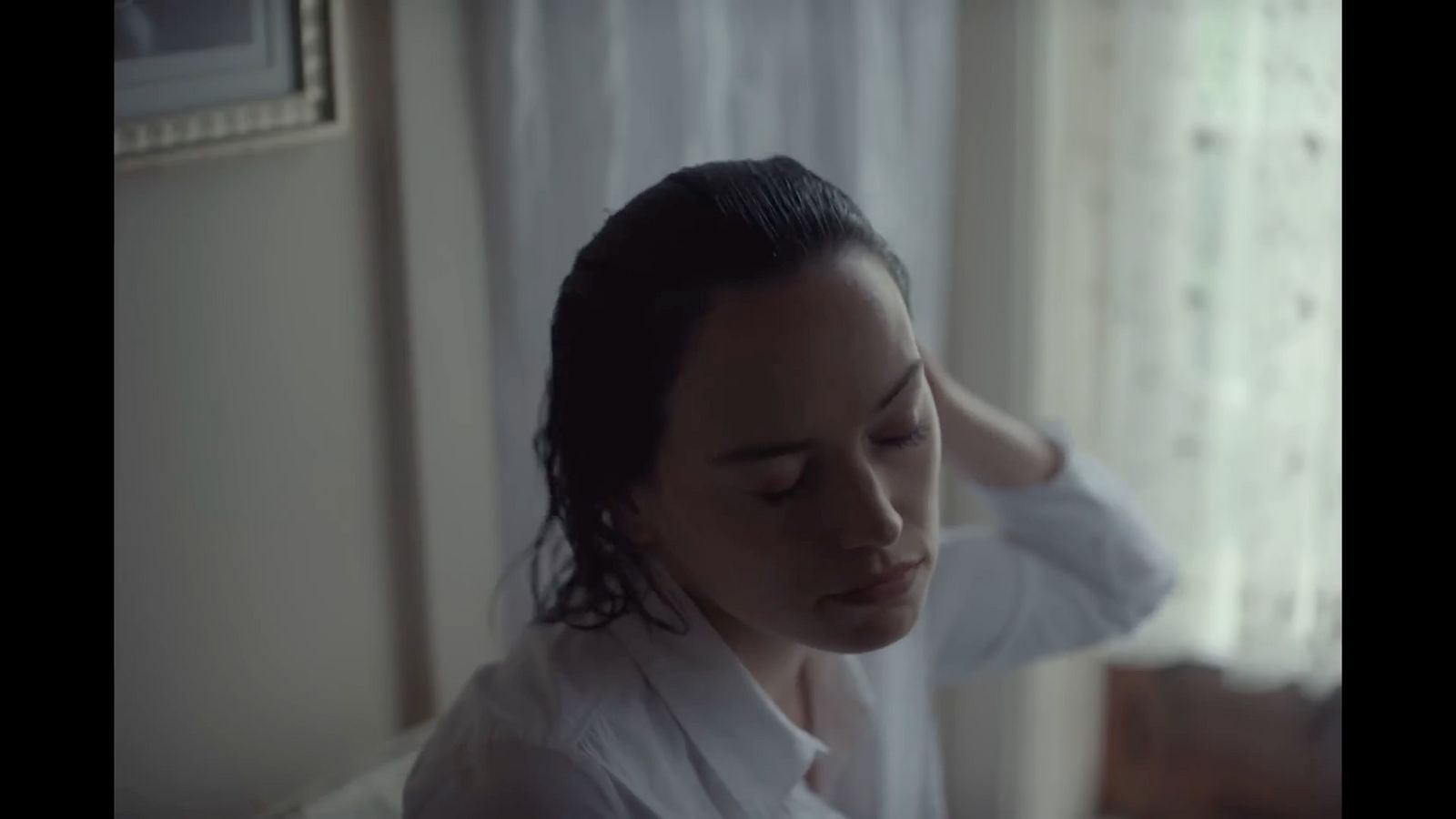 a woman in a white shirt is looking at her hair