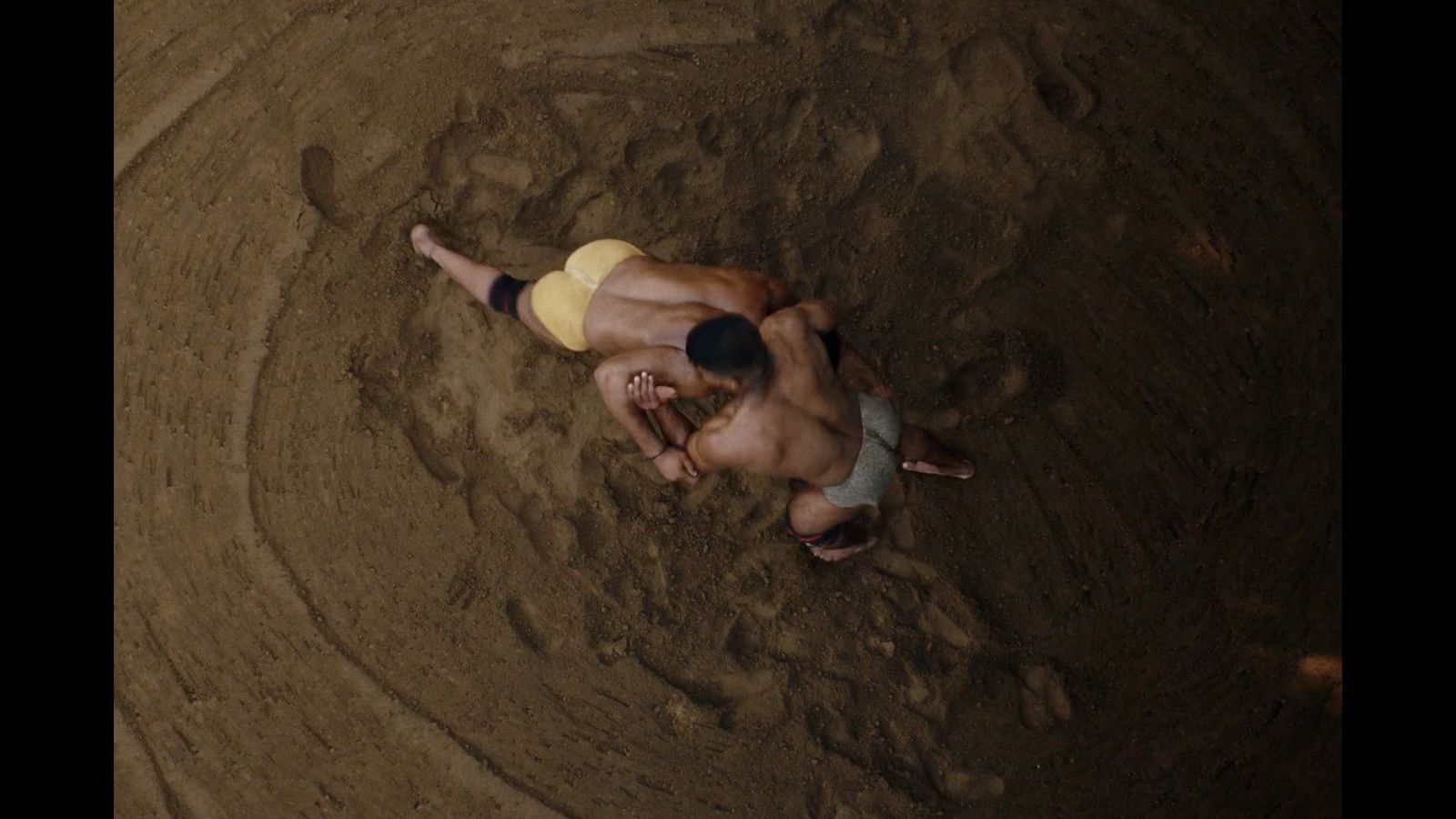 a couple of men are wrestling in the dirt