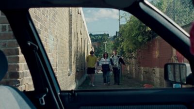 a group of people walking down a street next to a brick wall