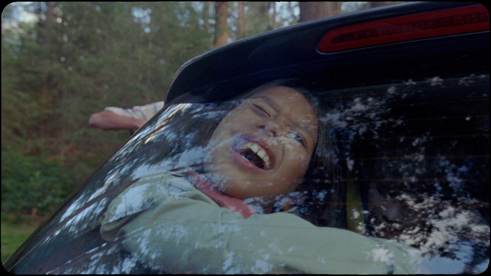 a young boy in the back of a car covered in snow