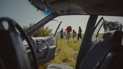 a group of people standing in a field next to a car