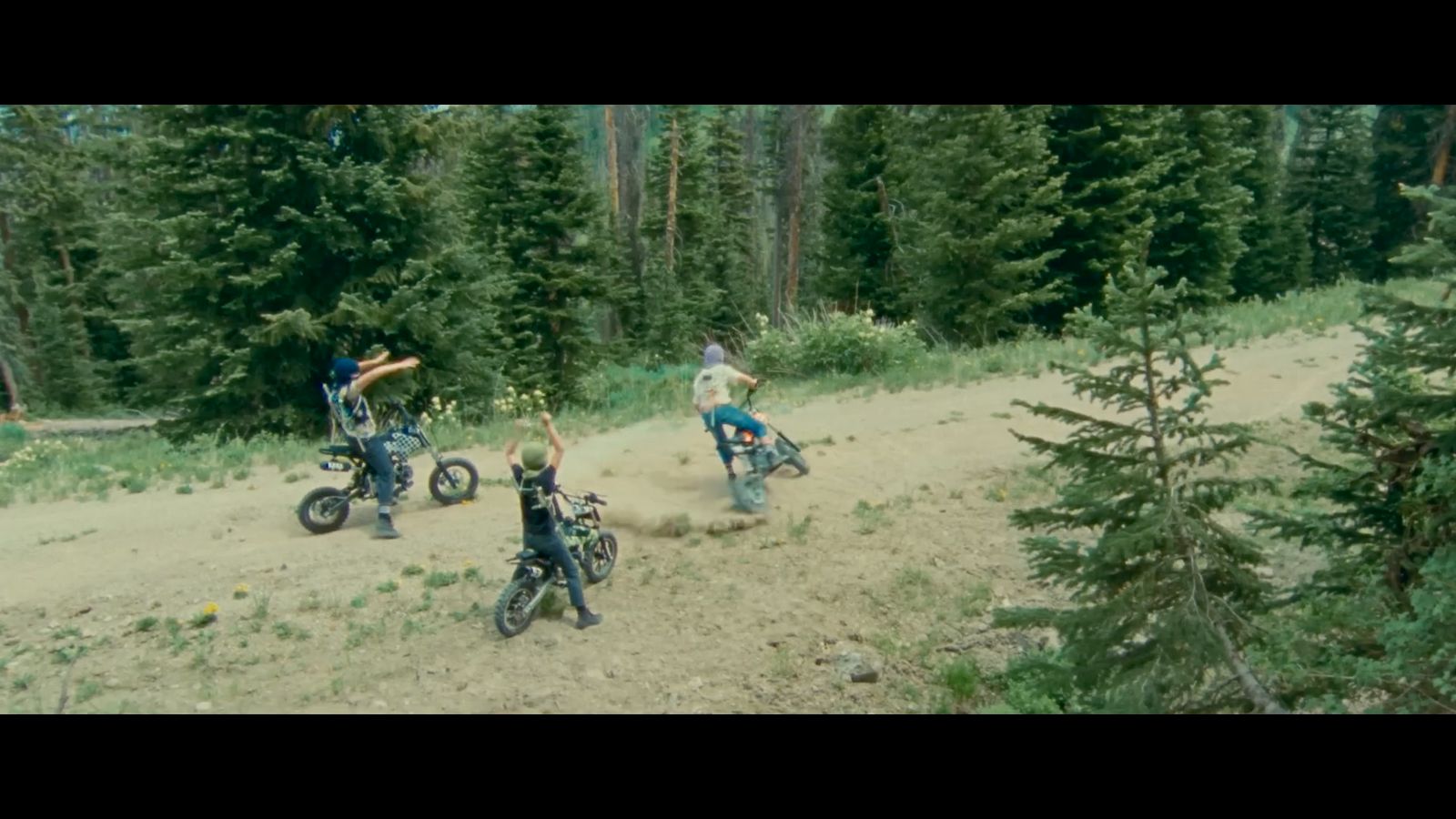 a group of people riding motorcycles on a dirt road