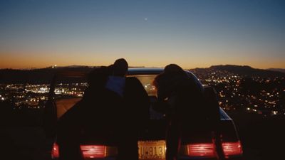 two people sitting in the back of a car at night