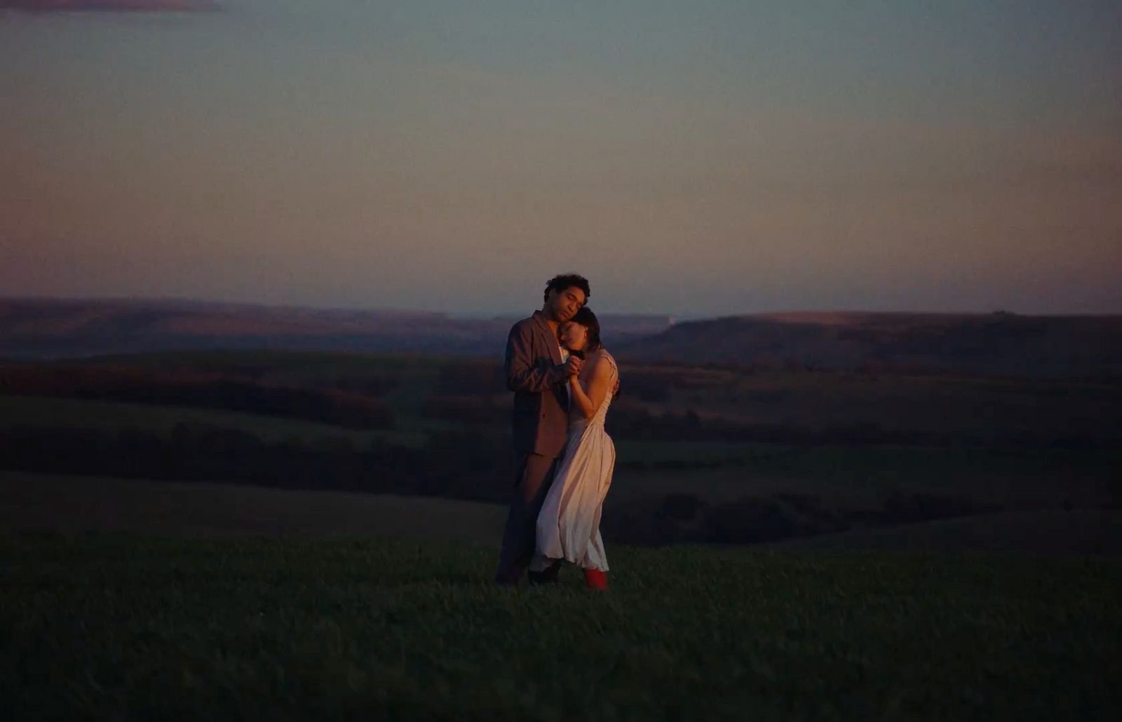 a man and a woman standing in a field at sunset