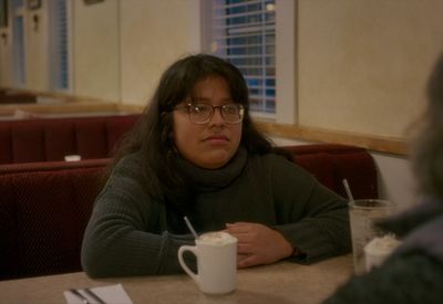 a woman sitting at a table with a cup of coffee