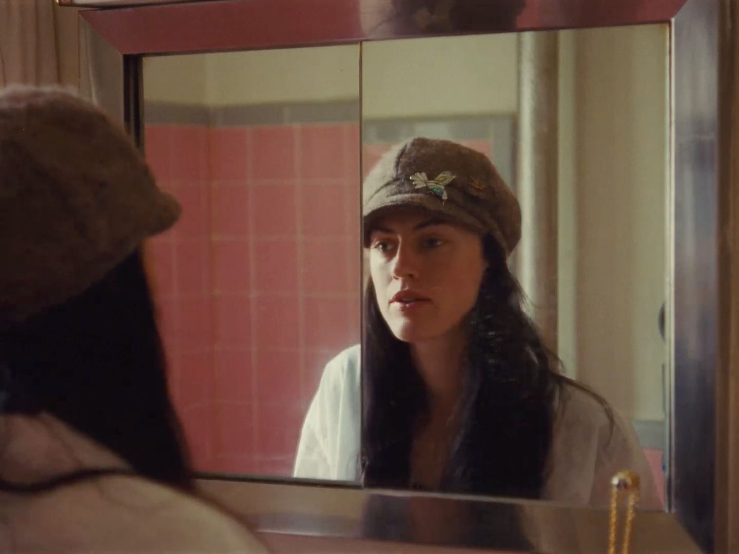 a woman in a hat looking at herself in a mirror