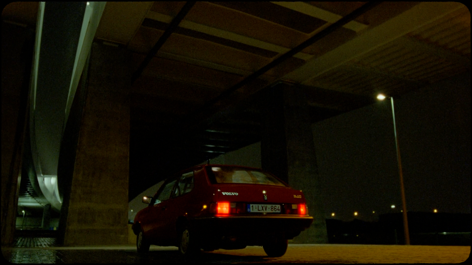 a red car parked under a bridge at night