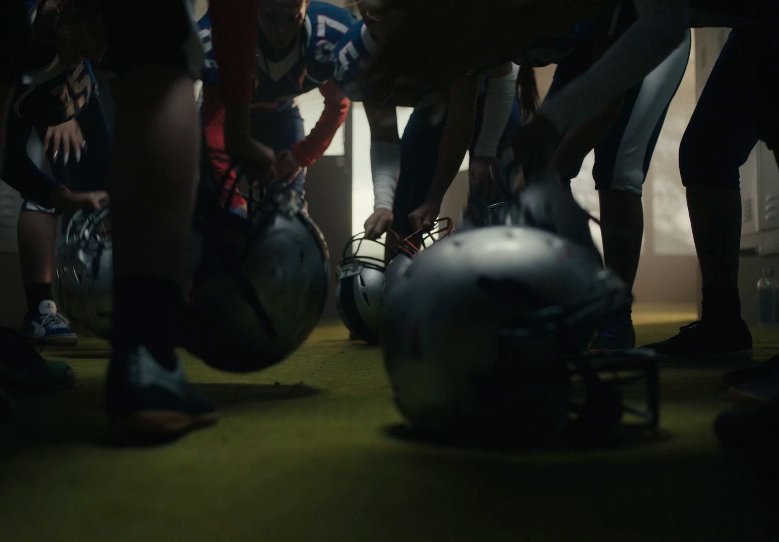 a group of football players kneel down in a huddle