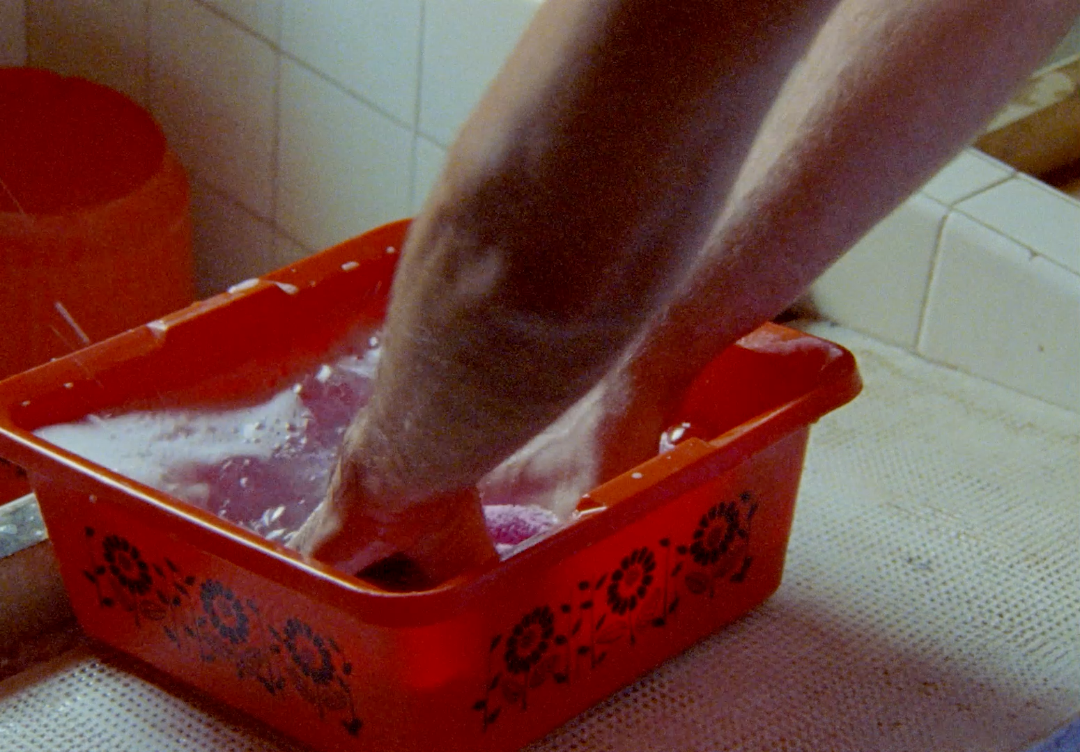 a person standing over a red container filled with liquid