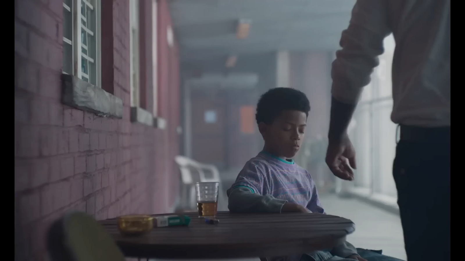 a young boy sitting at a table in front of a person