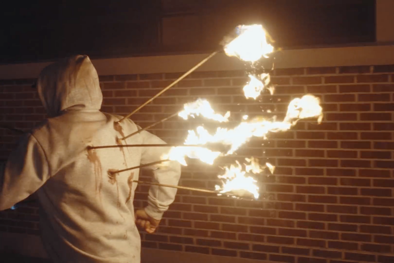 a person in a hoodie holding a stick with fire