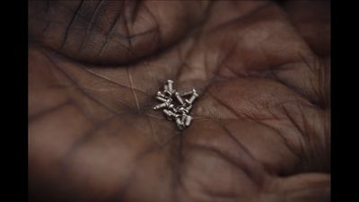 a person's hand holding a tiny silver object