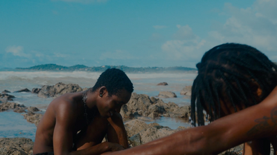 a couple of people sitting on top of a rocky beach