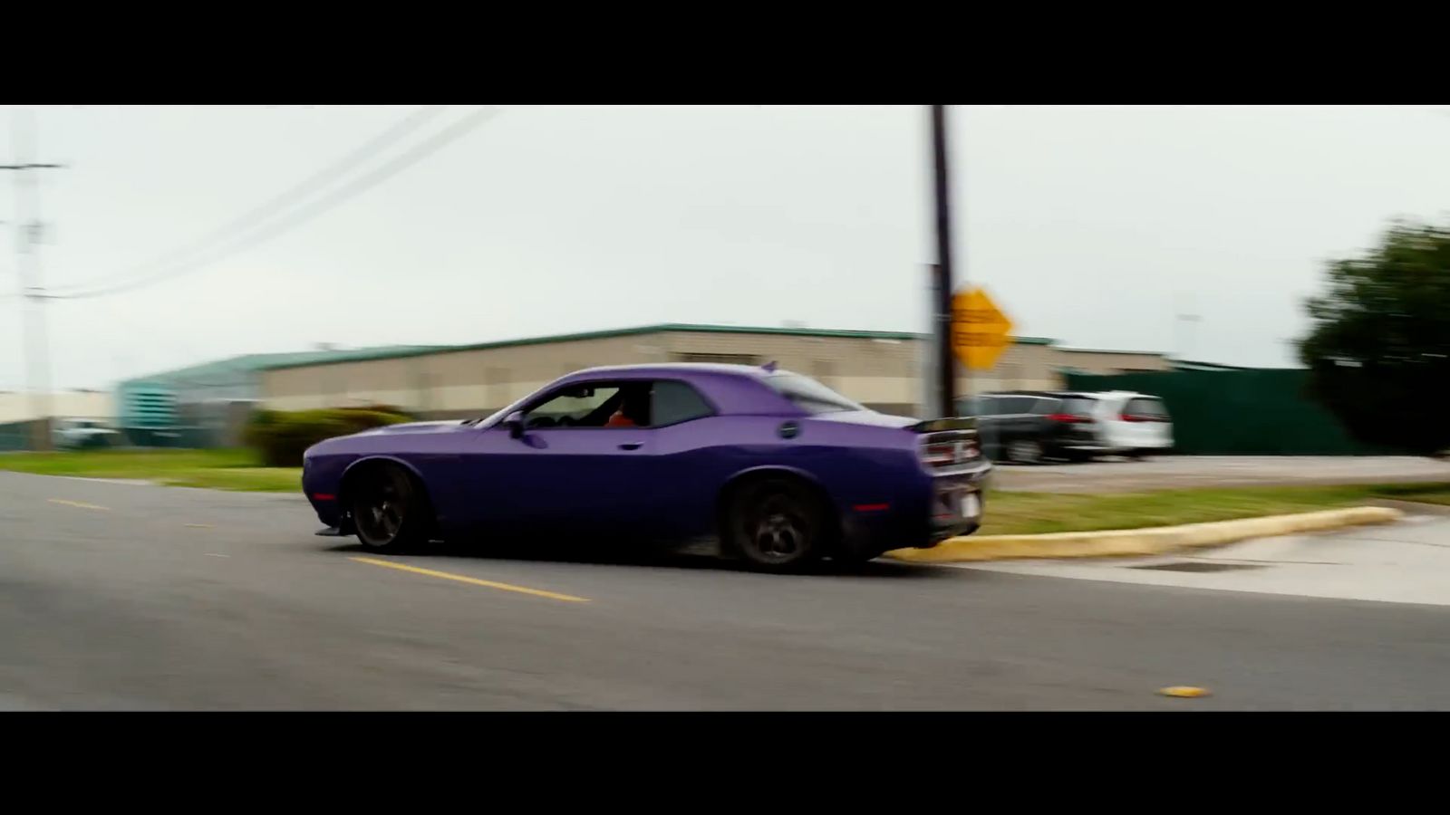 a purple car driving down a street next to a building