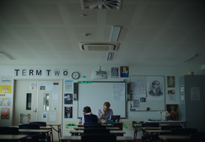 two people sitting at a table in a classroom