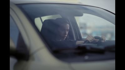 a woman sitting in a car looking at her cell phone