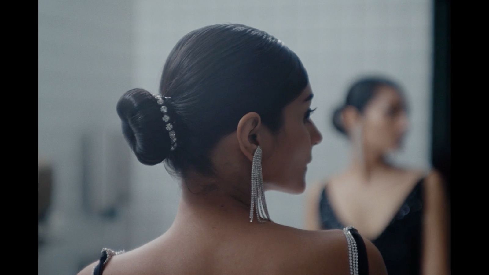 a woman in a black dress looking at herself in a mirror