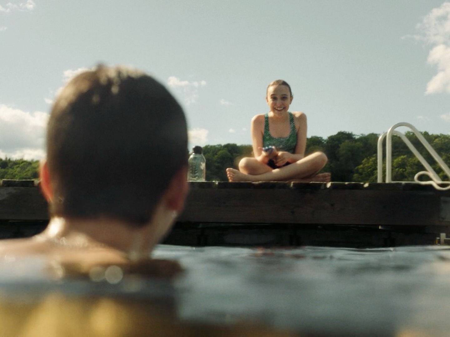 a woman sitting in a pool with a man watching