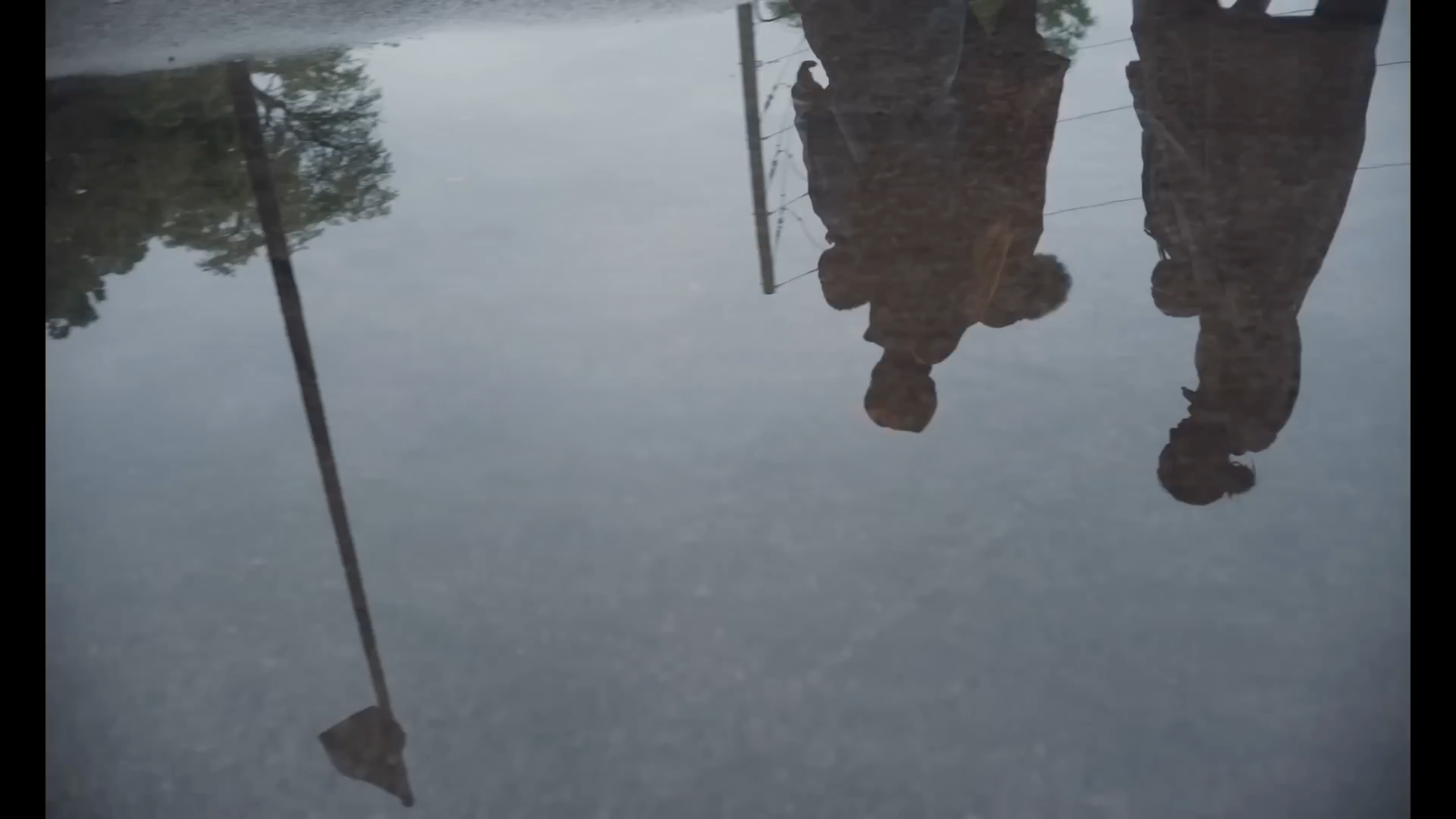 a reflection of two umbrellas in a puddle of water