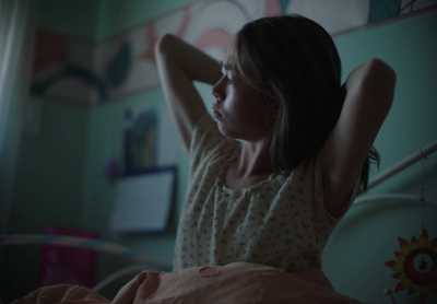 a girl sitting in bed with her arms behind her head