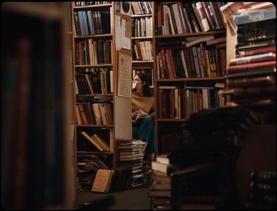 a woman sitting on a chair in a room full of books