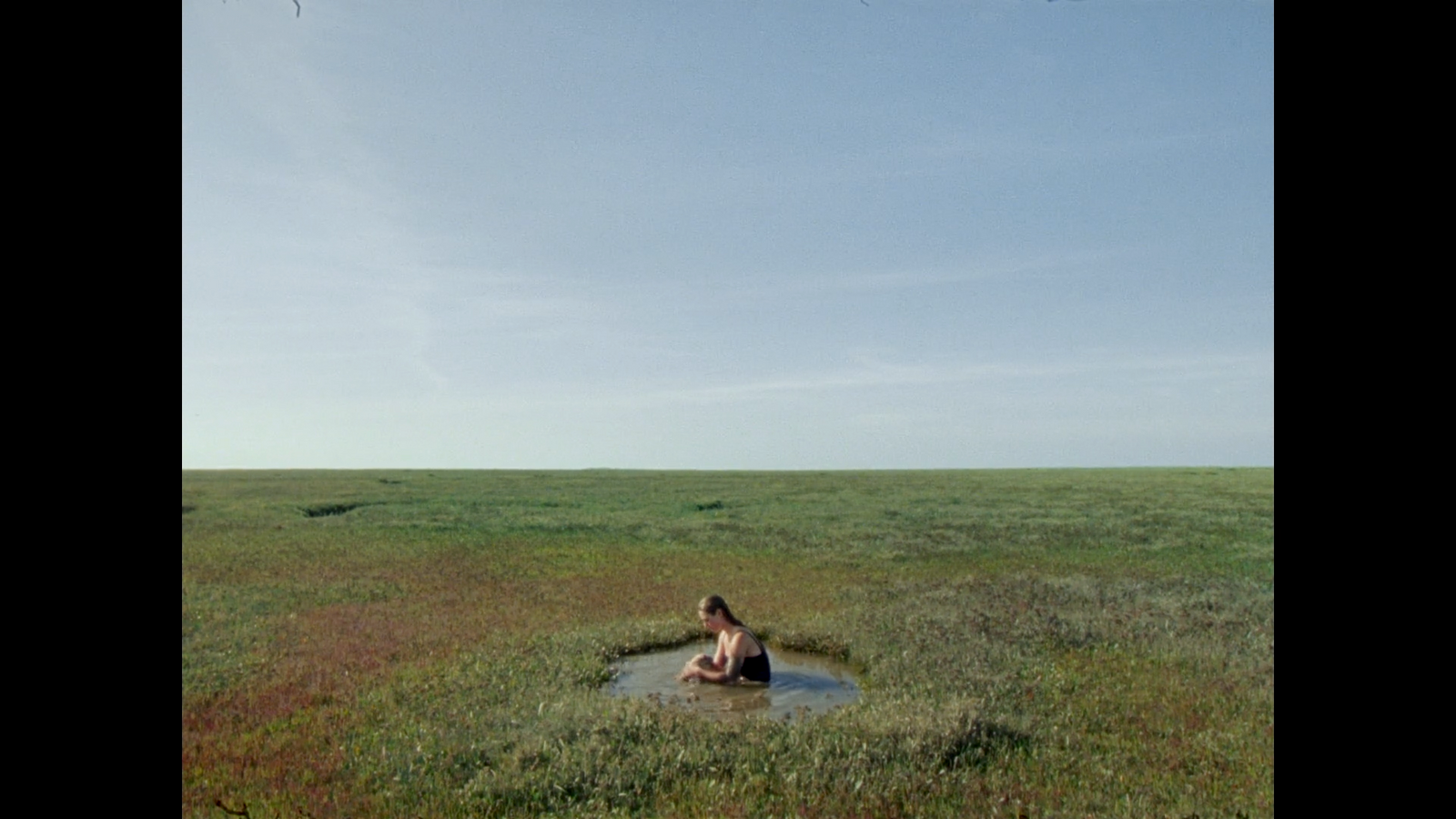 a person sitting in a field with a kite in the sky