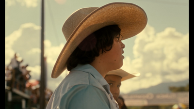 a young man wearing a cowboy hat and looking off into the distance