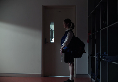 a woman standing in front of a door with a backpack