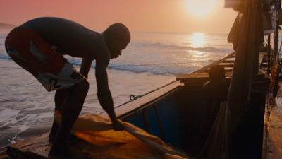 a man standing next to a boat in the ocean