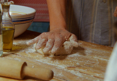 a person kneading dough on top of a wooden table