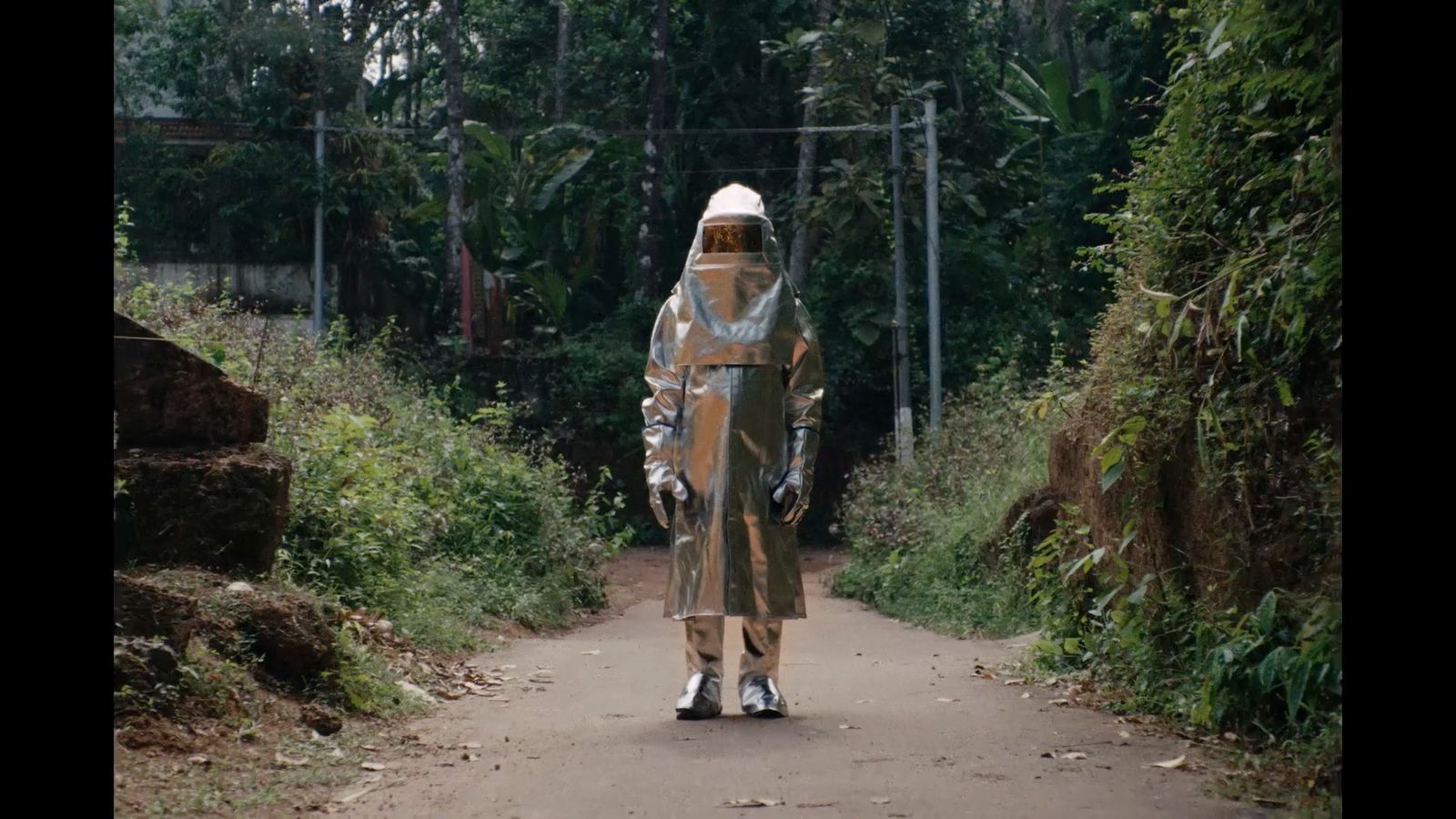 a man in a rain suit walking down a dirt road