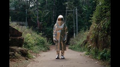 a man in a rain suit walking down a dirt road