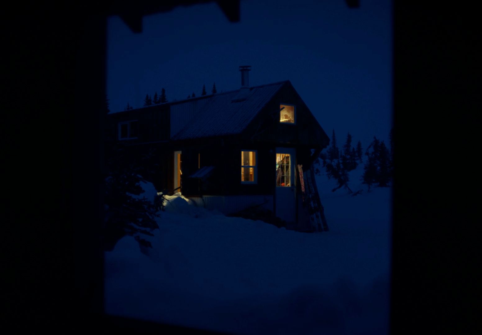 a house is lit up at night in the snow