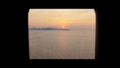 the sun is setting over the ocean as seen from an airplane