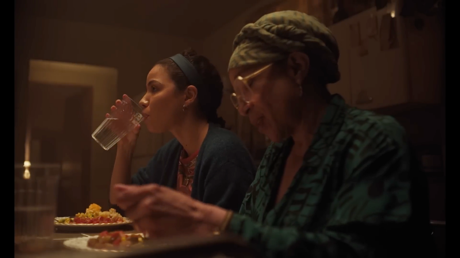 two women sitting at a table with a plate of food