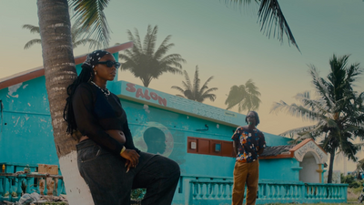 two men standing next to each other near a palm tree