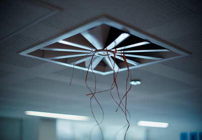 a room with a ceiling fan and wires hanging from the ceiling