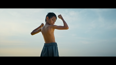 a young boy flexing his muscles on a beach