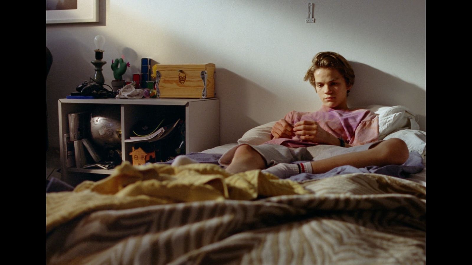 a person sitting on a bed with a pink shirt