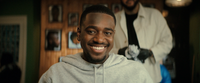 a man in a grey hoodie smiles at the camera