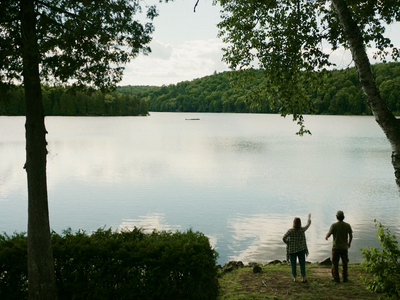 a couple of people standing next to a lake