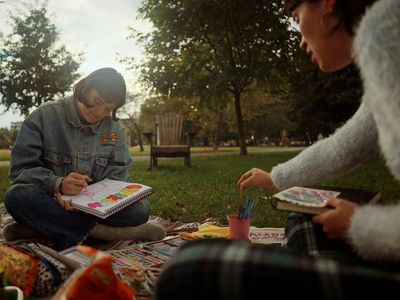 a woman sitting on a blanket holding a book