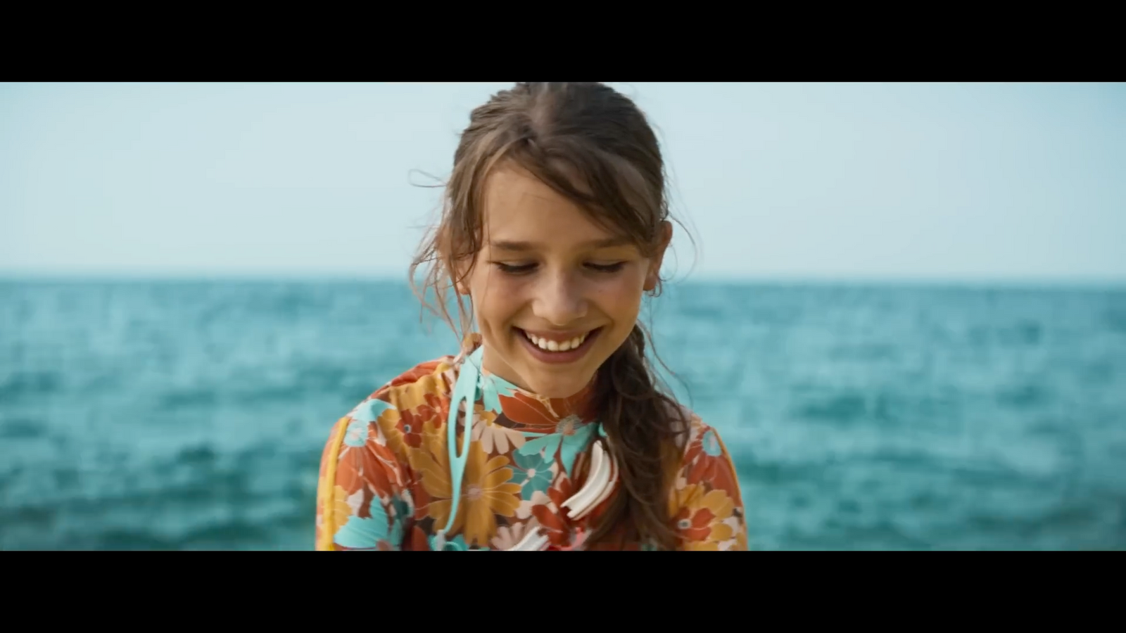 a young girl standing in front of a body of water