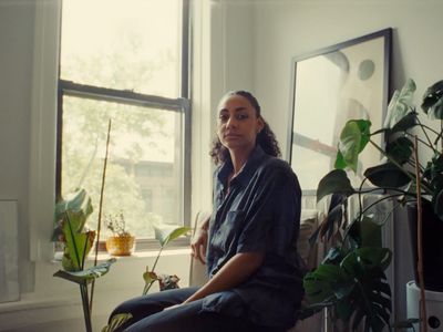 a woman sitting on a window sill next to a potted plant