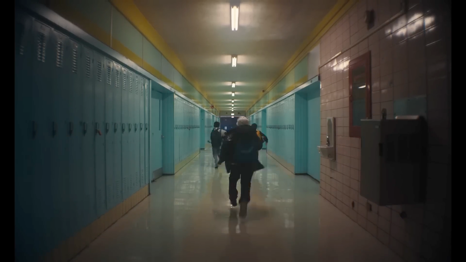 a person walking down a long hallway with lockers