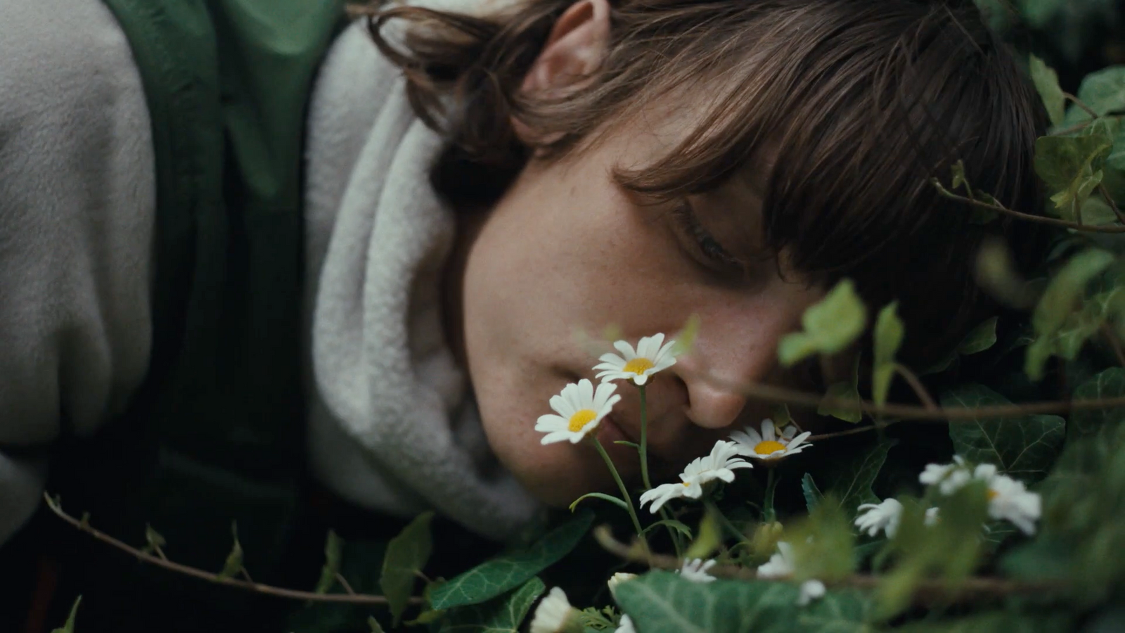 a young boy laying on the ground with a flower in his mouth