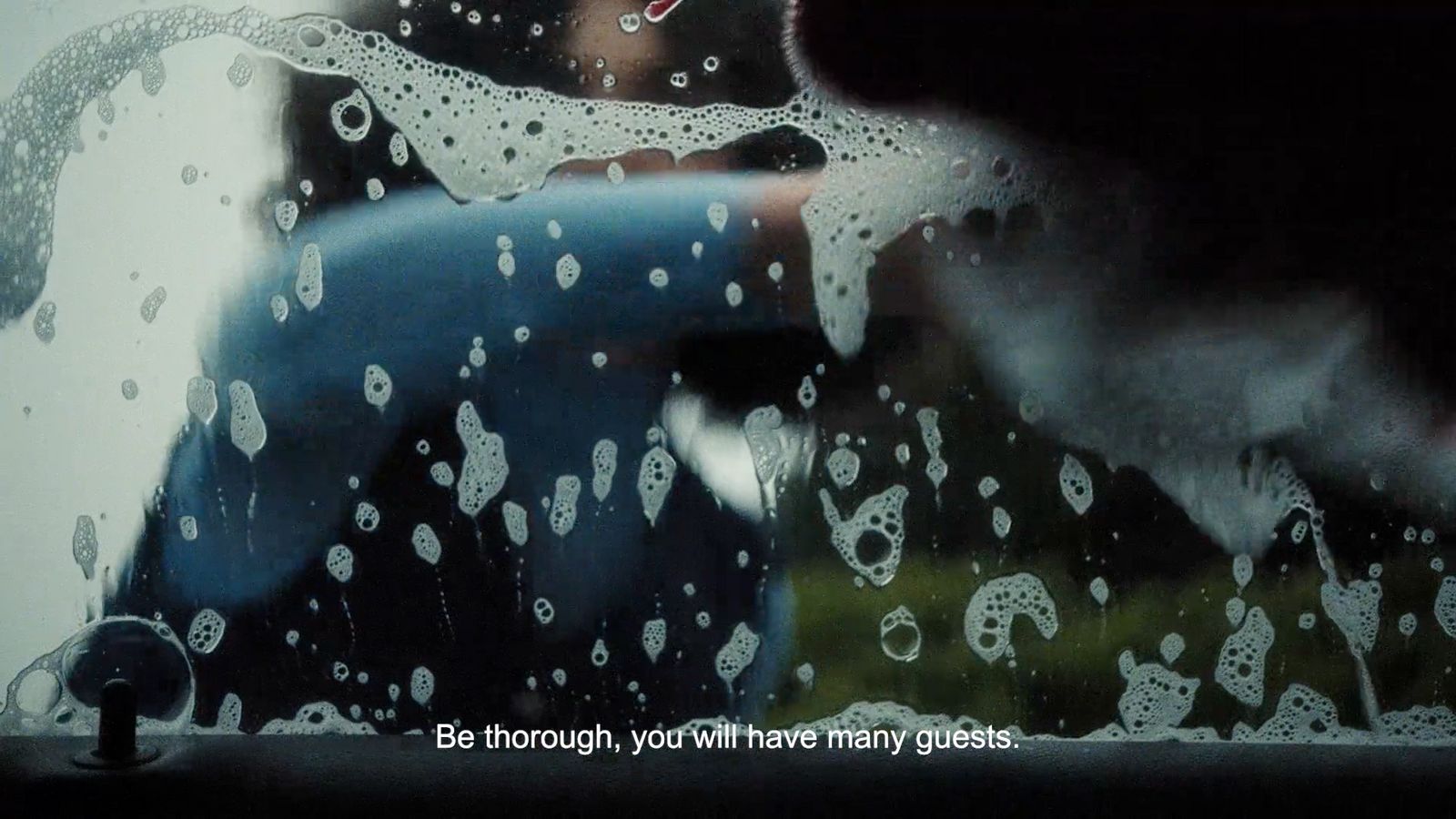 a person standing in front of a window covered in rain