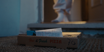 a box of pizza sitting on the floor next to a door